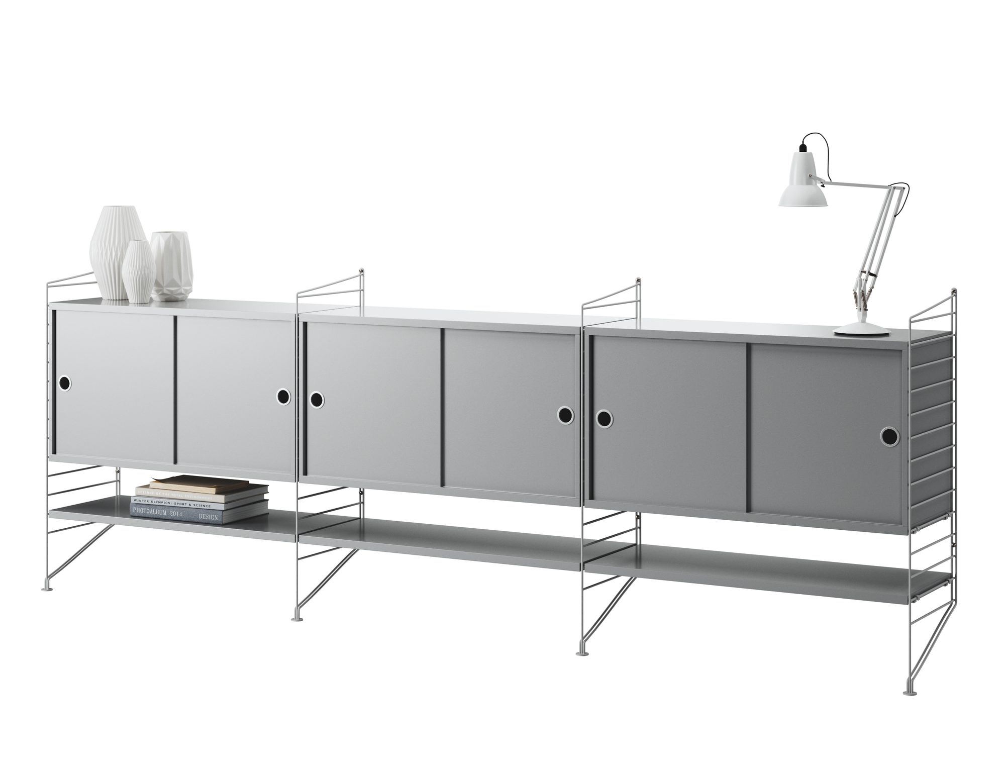 Grey String shelving system with cabinets, open shelves and a desk lamp on a white background