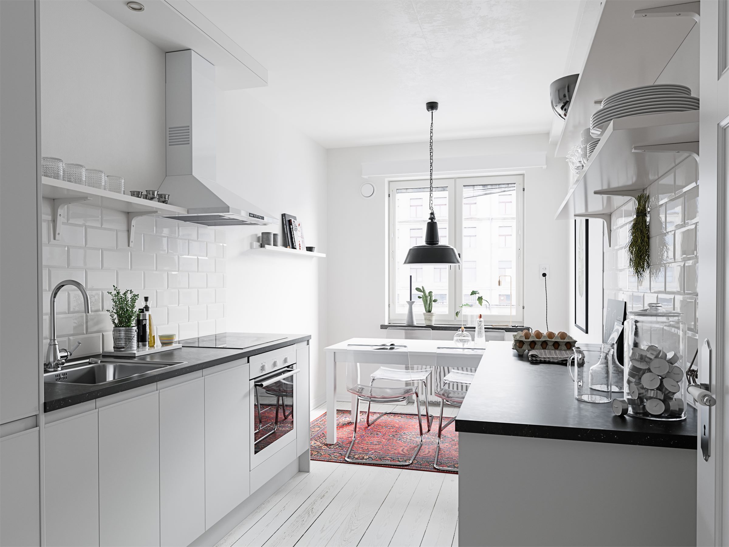 White kitchen with a black worktop, a range hood, open shelves and a small dining table by the window