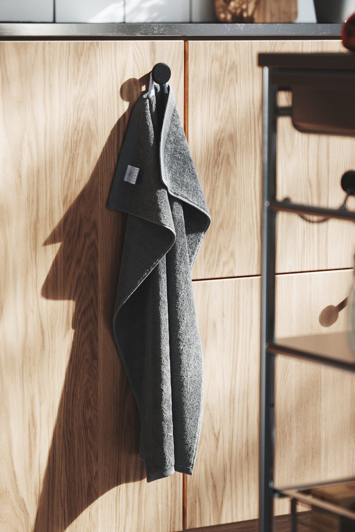 Grey hand towel hanging from a hook on a wooden cabinet